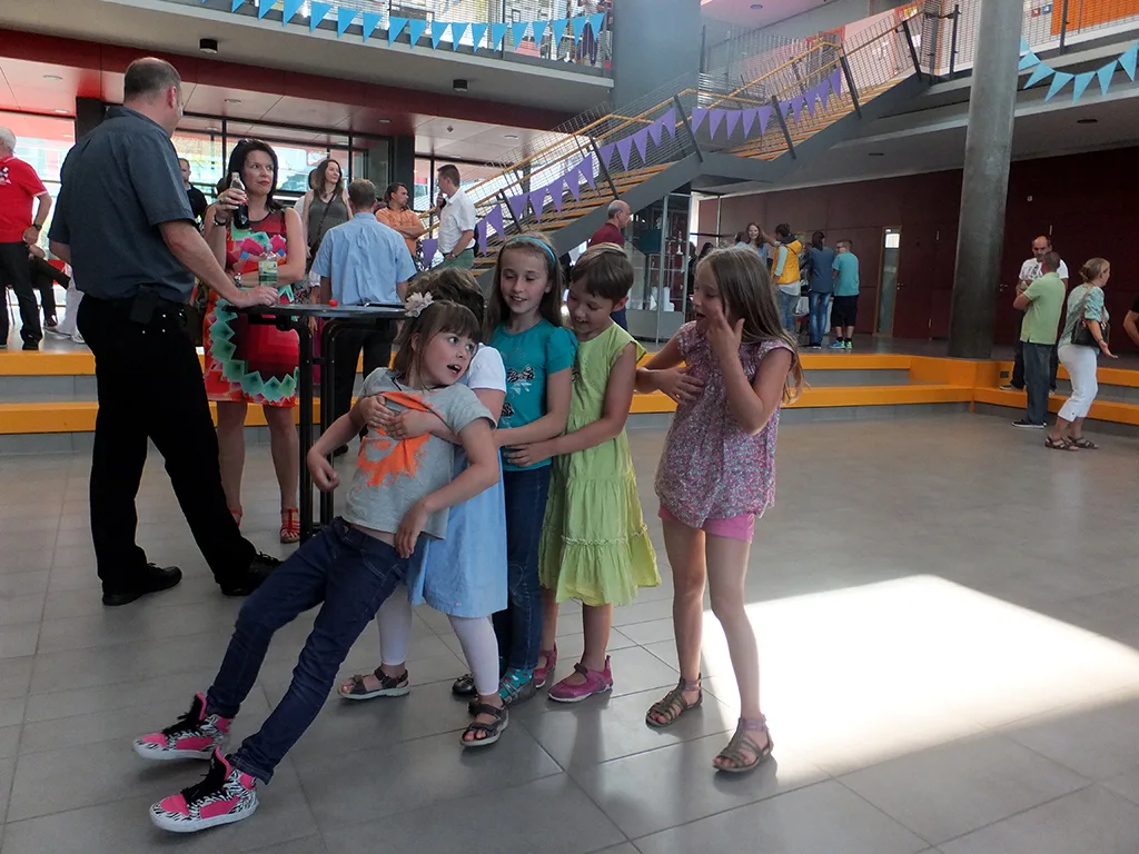 Kinder und eine Lehrkraft tanzen im Foyer.